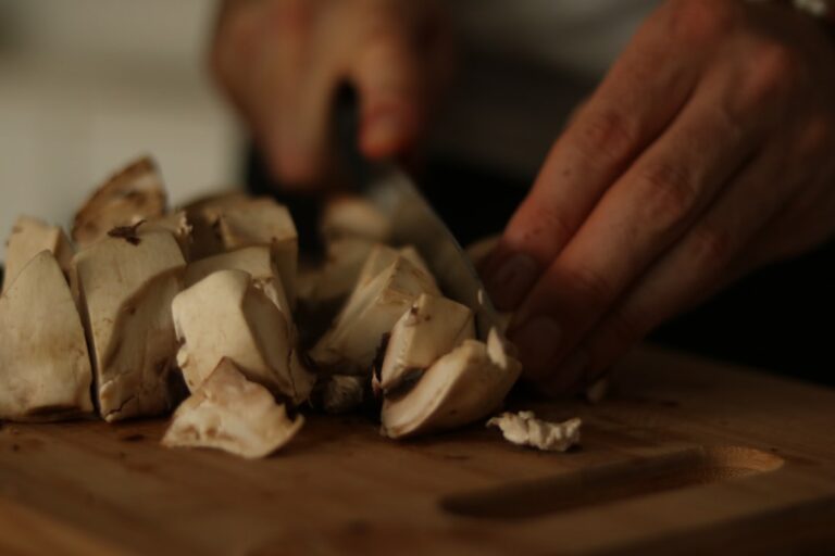 a person chopping mushrooms on a cutting board