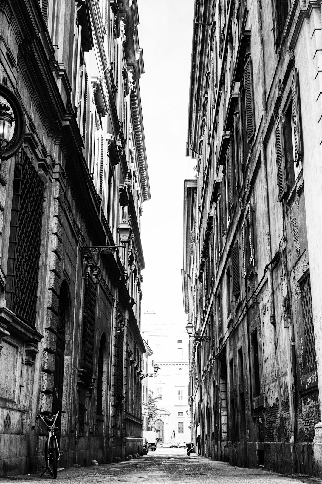 Buildings tower over a narrow alley in monochrome.