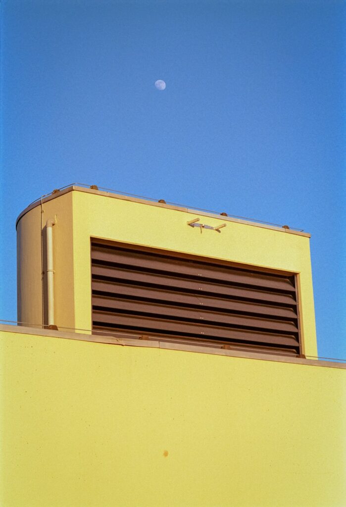 a yellow building with a half moon in the sky