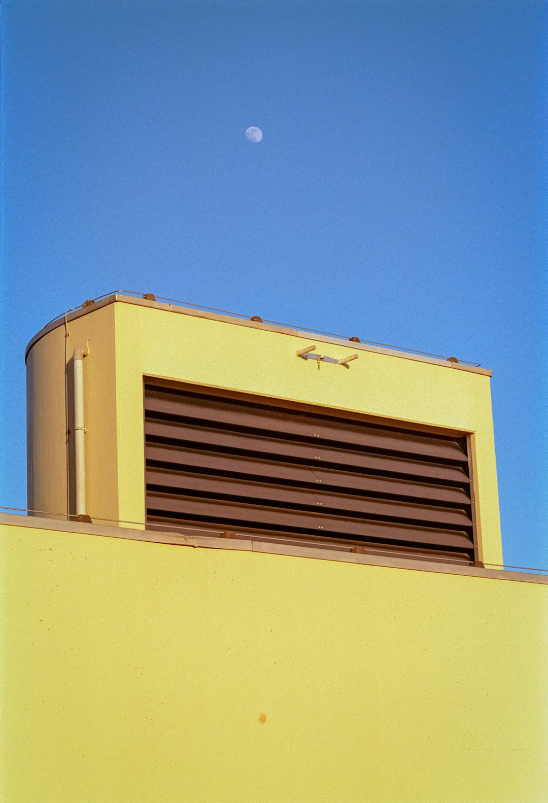 a yellow building with a half moon in the sky