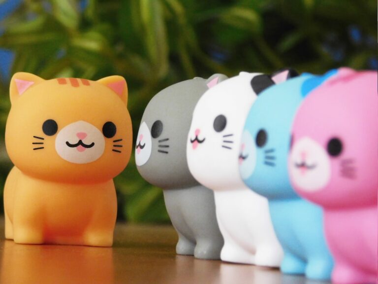 Row of colorful cat figurines with orange one in front