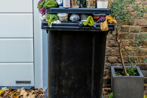 black trash bin with green leaves