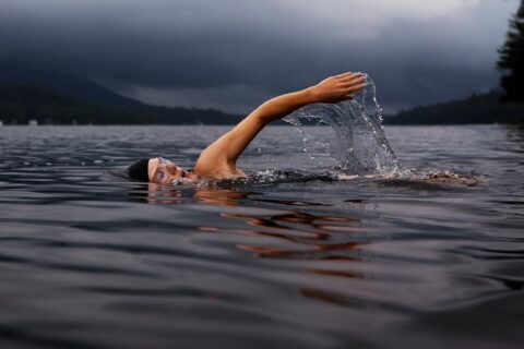 man swimming on body of water