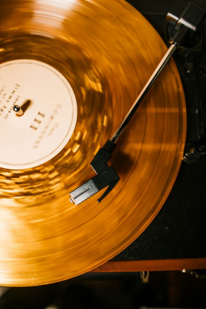 A translucent amber vinyl record spinning on a turntable with a black tonearm