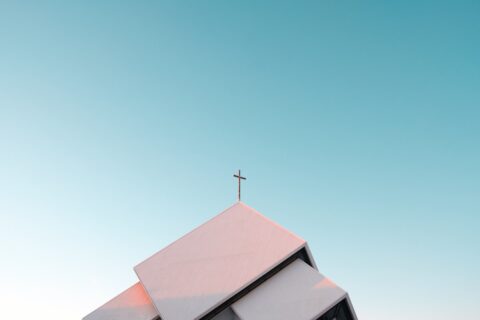 A white church roof with a cross against a clear blue sky