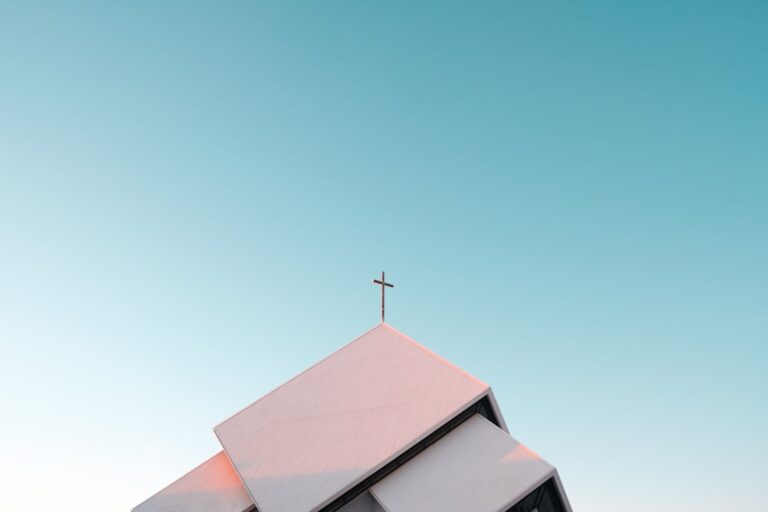 A white church roof with a cross against a clear blue sky