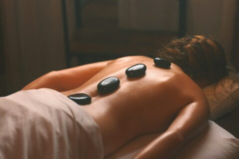 a woman laying on a bed with hot stones on her back