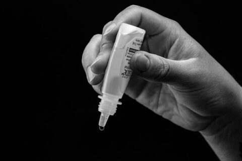 Hand holding eye drops, ready to administer