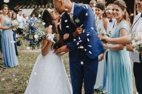 man in blue suit kissing woman in white wedding dress